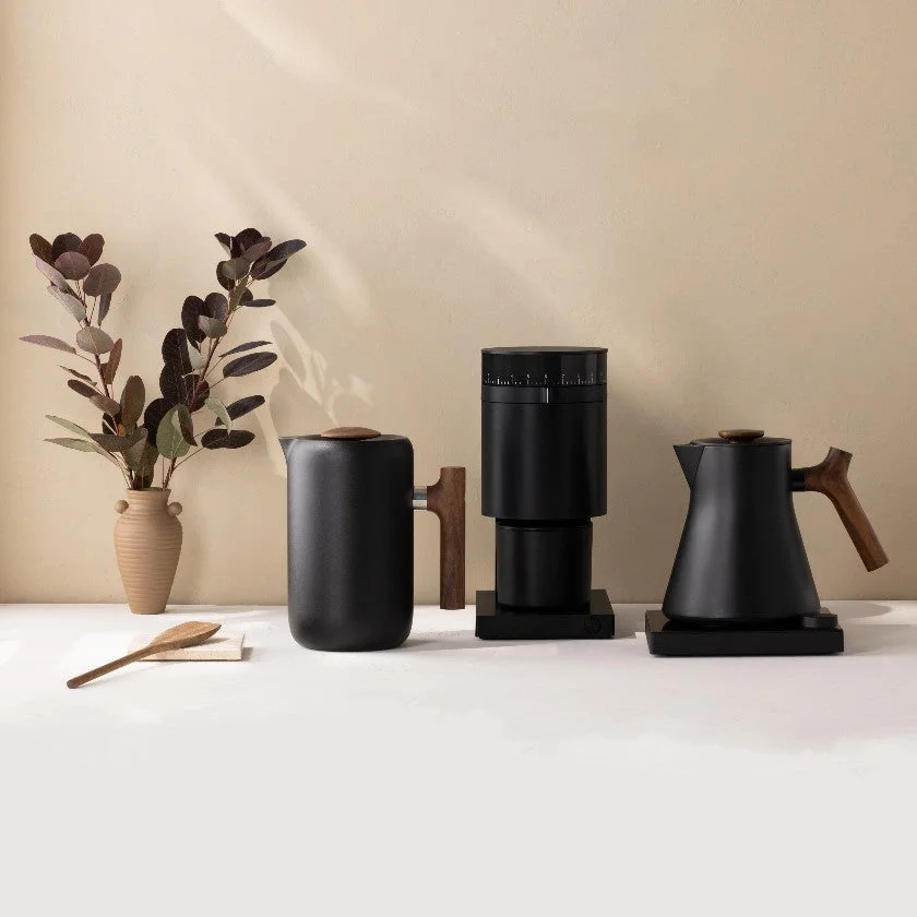 Black coffee grinder, kettle and canister arranged on a table